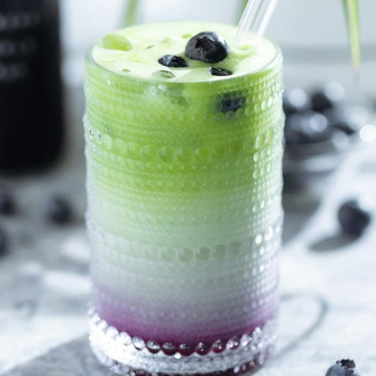 matcha smoothie with blueberries in a glass on a light background
