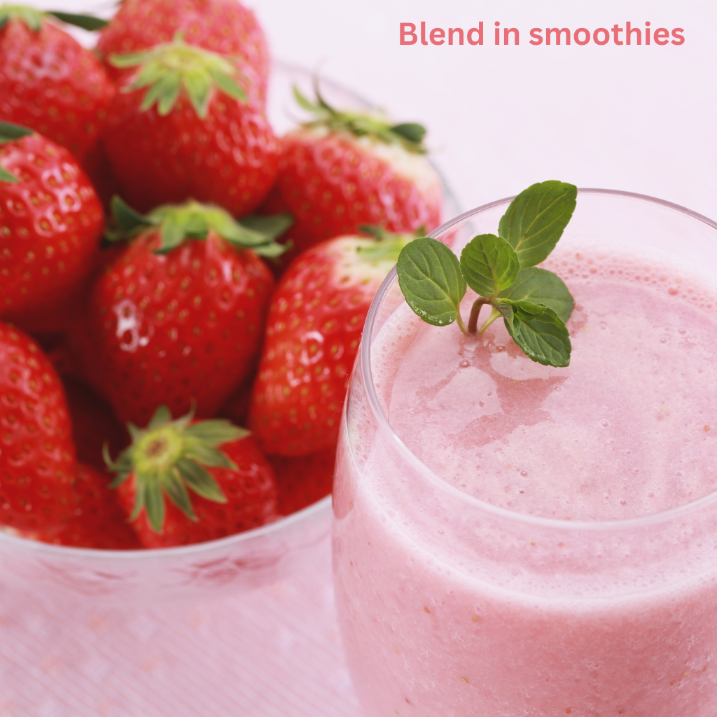 A close-up shot of a pink strawberry smoothie in a clear glass, topped with fresh mint. The glass is positioned in front of a slightly blurred glass bowl full of bright red, whole fresh strawberries. The text "Blend in smoothies" is visible in the upper-right corner.