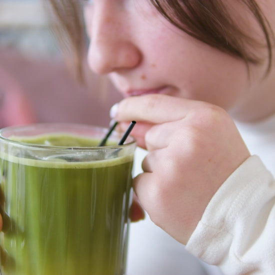 A video of female sipping matcha from a clear glass using a straw