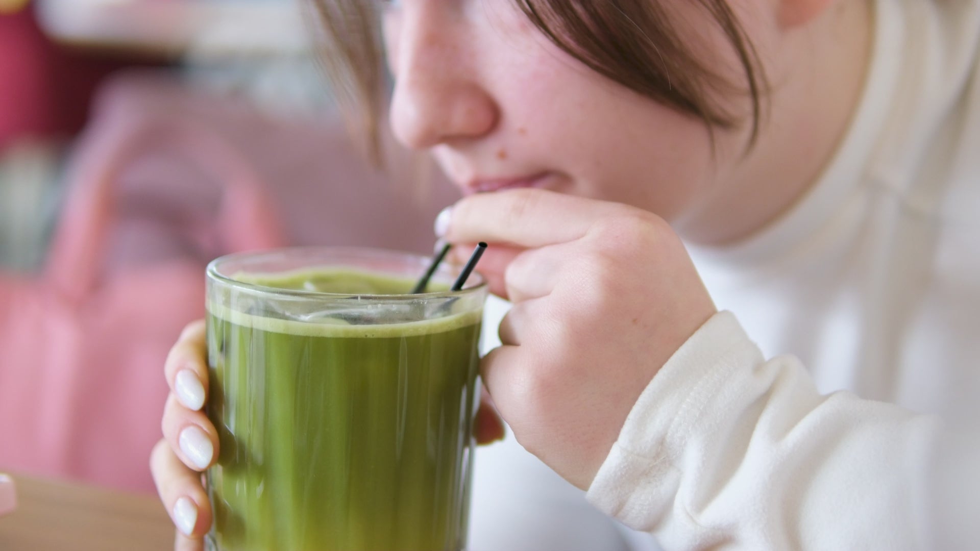 A video of female sipping matcha from a clear glass using a straw